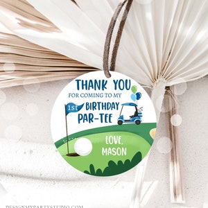 Peut inclure: Une &eacute;tiquette ronde de remerciement avec un terrain de golf vert, une voiturette de golf bleue, une balle de golf blanche et un drapeau bleu avec le texte "1st Birthday Par-Tee". L'&eacute;tiquette comprend &eacute;galement le texte "Thank You for coming to my 1st Birthday Par-Tee Love, Mason".