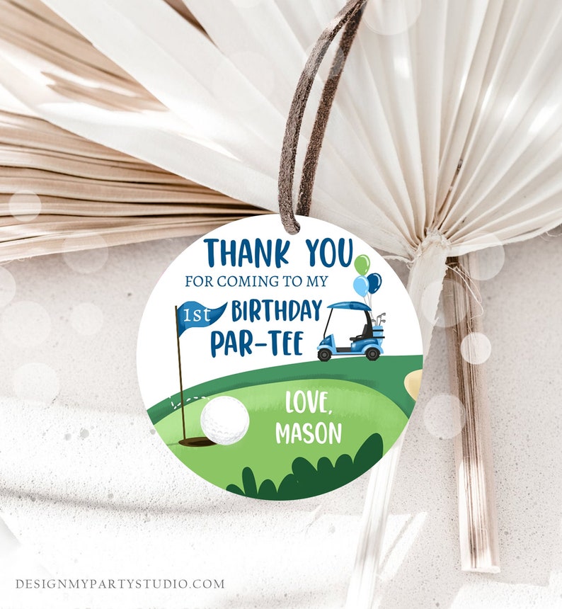 Peut inclure: Une &eacute;tiquette ronde de remerciement avec un terrain de golf vert, une voiturette de golf bleue, une balle de golf blanche et un drapeau bleu avec le texte "1st Birthday Par-Tee". L'&eacute;tiquette comprend &eacute;galement le texte "Thank You for coming to my 1st Birthday Par-Tee Love, Mason".
