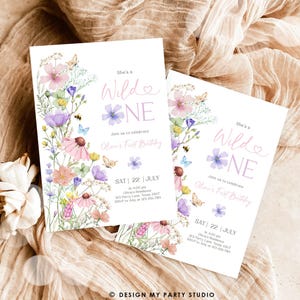 May include: A printable invitation for a first birthday party. The invitation features a watercolor floral design with butterflies and the text "She's a Wild One" in pink and purple. The invitation includes the date, time, location, and RSVP information.