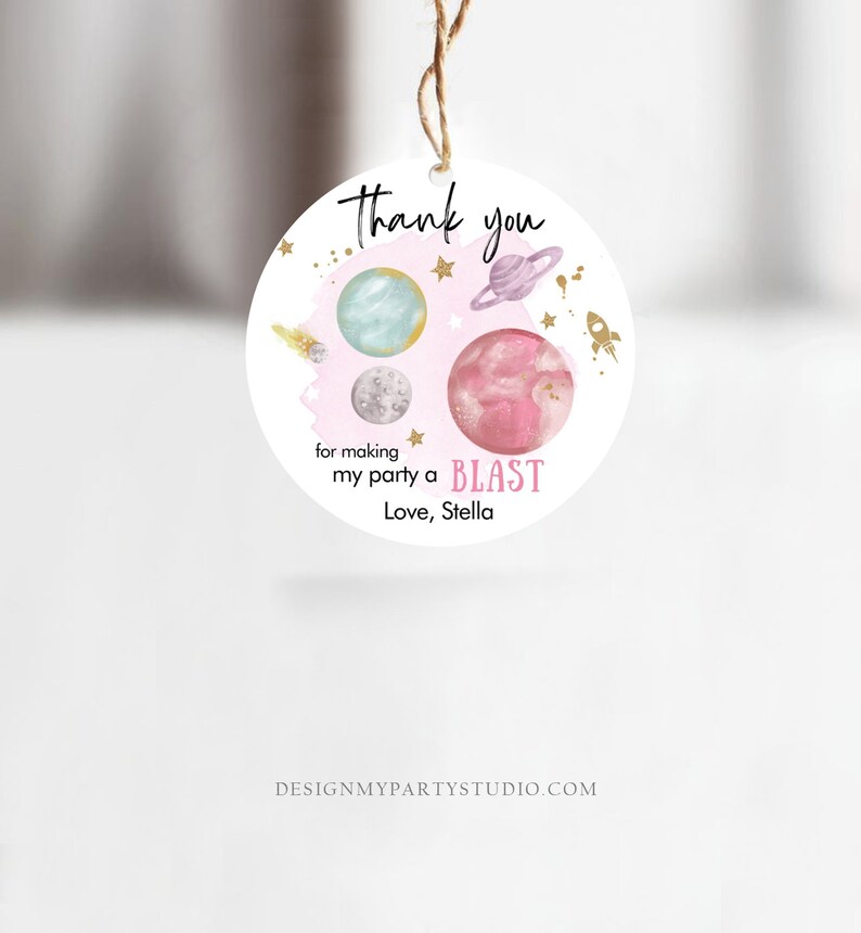 May include: Round pink and white thank you tag with a space theme. It features planets, stars, and a rocket ship. The text reads "Thank you for making my party a BLAST Love, Stella".