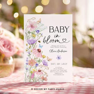 May include: A baby shower invitation with a floral design. The invitation says "Baby in Bloom" and features a watercolor illustration of pink, purple, and blue flowers with butterflies. The text includes the date, time, and location of the shower, as well as the name of the guest of honor, Olivia Anderson.