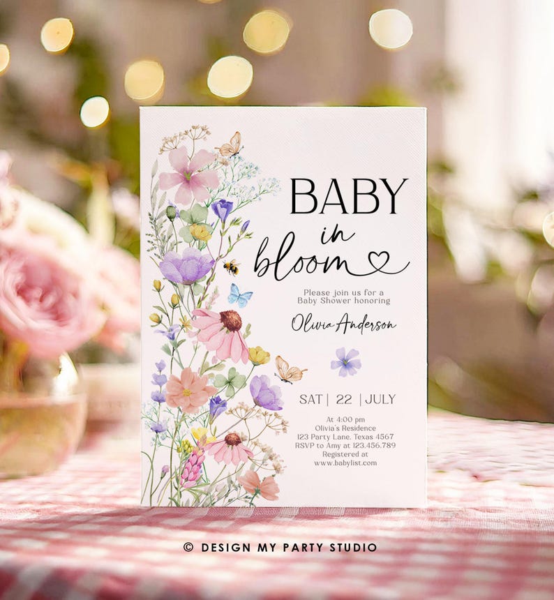 May include: A baby shower invitation with a floral design. The invitation says "Baby in Bloom" and features a watercolor illustration of pink, purple, and blue flowers with butterflies. The text includes the date, time, and location of the shower, as well as the name of the guest of honor, Olivia Anderson.