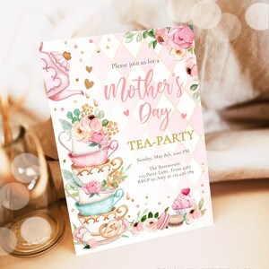May include: Pink and gold invitation for a Mother's Day tea party. The invitation features a stack of teacups with floral designs and a teapot. The text reads "Please join us for a Mother's Day Tea-Party" and includes the date, time, location, and RSVP information.