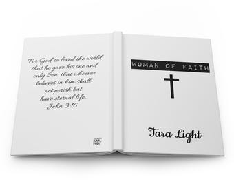 May include: Open white journal with the text "For God so loved the world...John 3:16" on the left page. The right page reads "WOMAN OF FAITH" above a black cross and "Tara Light" below.