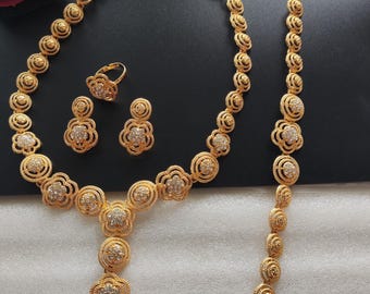 May include: A gold-tone jewelry set with a necklace, bracelet, ring, and earrings. The jewelry features a floral design with clear rhinestones.