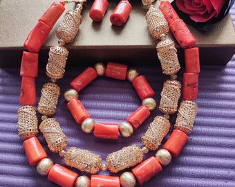 May include: A coral bead necklace and bracelet set with gold-toned accents. The necklace has two strands of coral beads and the bracelet has one strand. The beads are all cylindrical and have a smooth, polished finish. The gold-toned accents are small, decorative pieces that are attached to the beads. The set is a beautiful and elegant piece of jewelry that would be perfect for any occasion.