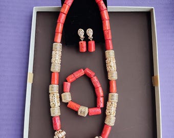 May include: A coral necklace, bracelet, and earrings set. The necklace and bracelet are made of red coral beads with gold accents. The earrings are red coral with gold accents.