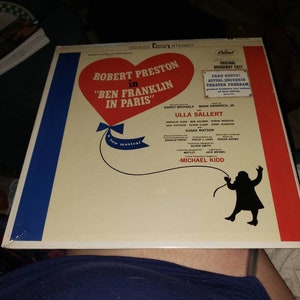 May include: A vintage vinyl record album cover for the musical "Ben Franklin in Paris" featuring Robert Preston. The cover has a red heart-shaped design with blue and red stripes, and includes the text "Original Broadway Cast".