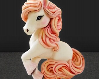 Könnte beinhalten: Eine weiße und rosa Einhornfigur mit fließender Mähne und Schweif. Das Einhorn hat eine hellrosa Mähne und Schweif mit einem Hauch von Pfirsich. Die Figur ist vor einem dunklen Hintergrund platziert.