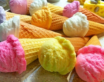 May include: Assortment of colourful ice cream cones with different flavours, including pink, yellow, and white. The cones are made of waffle and have a variety of toppings.