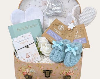 Cesta de regalo para mamás primerizas: patucos, manoplas, té relajante y baúl de recuerdos.