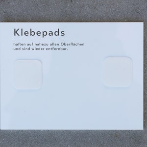 Befestigung des Türschildes mit Klebepads. Sie haften auf nahezu allen Oberflächen und sind wieder rückstandslos entfernbar.