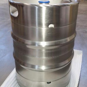 May include: A stainless steel keg with a blue cap and two handles. The keg has a smooth, polished finish and is designed for storing and dispensing beverages.