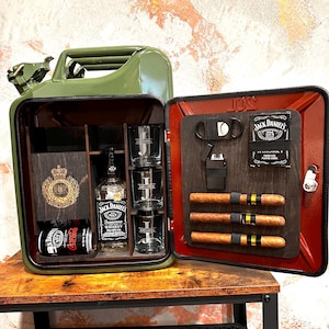 Peut inclure: Un bidon métallique vert transformé en bar. À l'intérieur, une bouteille de whisky Jack Daniel's, quatre verres, une canette de Coca-Cola et des cigares. La porte du meuble contient un coupe-cigare et d'autres cigares.