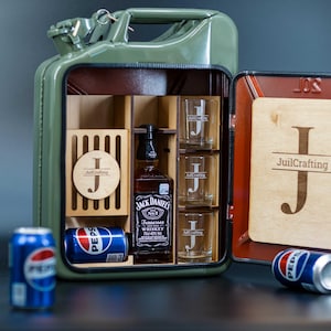 Peut inclure: Un bidon Jerry vert en métal transformé en bar. À l'intérieur, des verres à shot, une bouteille de whisky Jack Daniel's et des éléments en bois. Deux canettes de Pepsi sont devant le meuble.