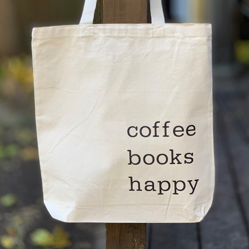 May include: A white canvas tote bag with the text "coffee books happy" printed in black.
