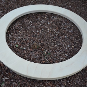 May include: A plain, light wood ring, lying on a bed of brown wood chips.