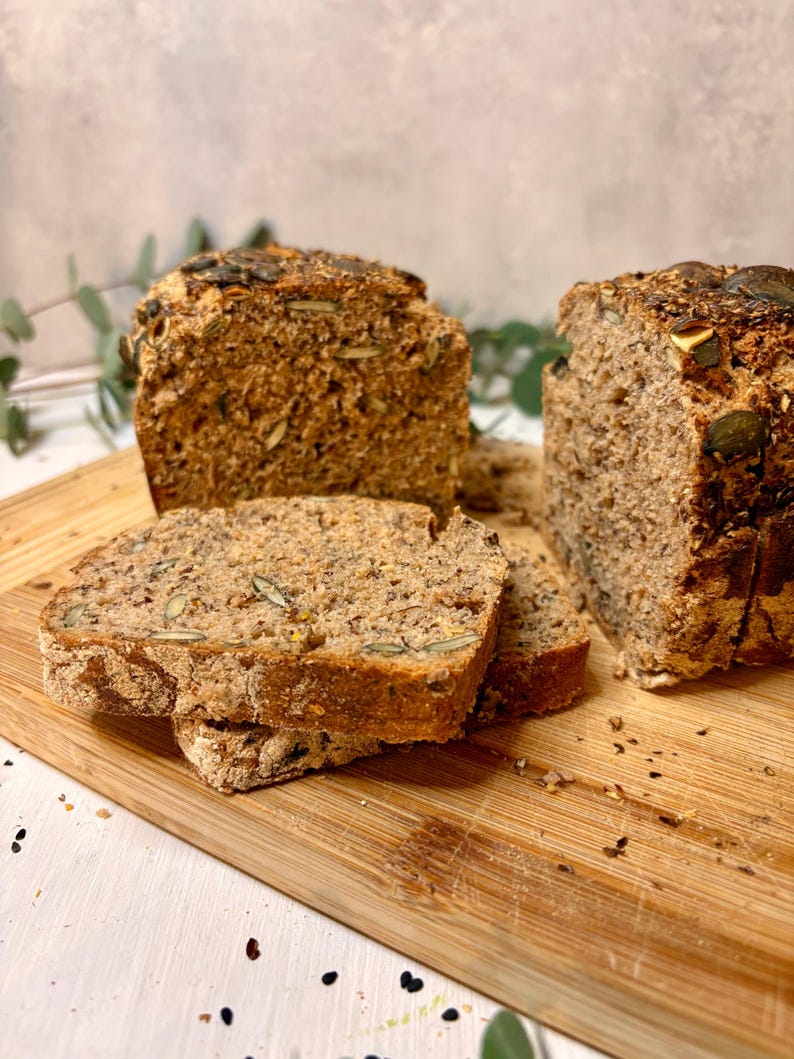 May include: A sliced loaf of freshly baked bread, with visible seeds and grains. The bread is a golden brown colour and sits on a wooden chopping board. The slices are ready to be served, highlighting the bread's texture and ingredients.