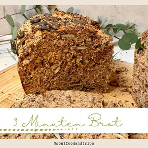 May include: A loaf of freshly baked bread, sliced and ready to serve. The bread is a rich brown colour, topped with seeds, and has a rustic texture. The text "3 Minuten Brot" is visible.