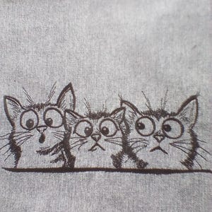 Könnte beinhalten: Ein grauer Stoff mit einer schwarzen Illustration von drei überraschten Katzen mit großen Augen. Die Katzen sind im Cartoon-Stil gezeichnet, mit Schnurrhaaren und ausdrucksstarken Gesichtern. Der Stoff hat ein strukturiertes Aussehen.