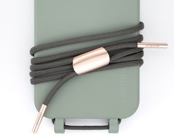 May include: A sage green phone case with a dark gray lanyard and a rose gold accent. The lanyard is wrapped around the case and has a rose gold slider.