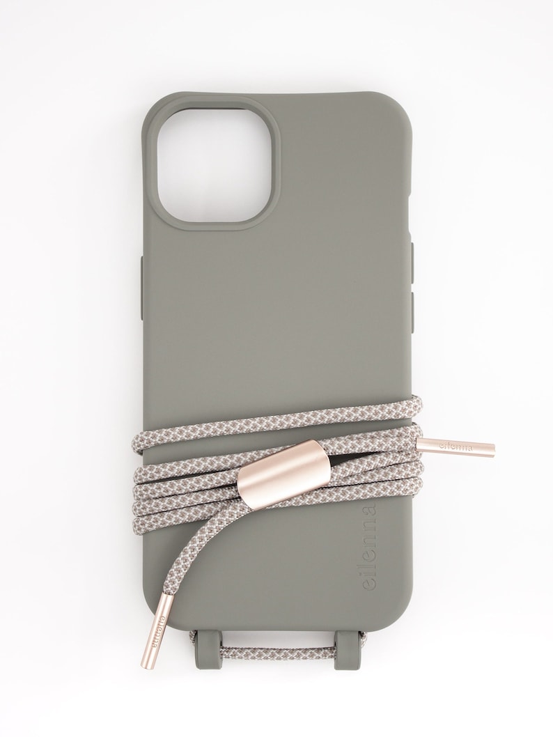 May include: A gray phone case with a matching rope strap. The case has a camera cutout and button covers. The rope strap is gray and white with rose gold metal accents. The brand name "eilenna" is printed on the strap.