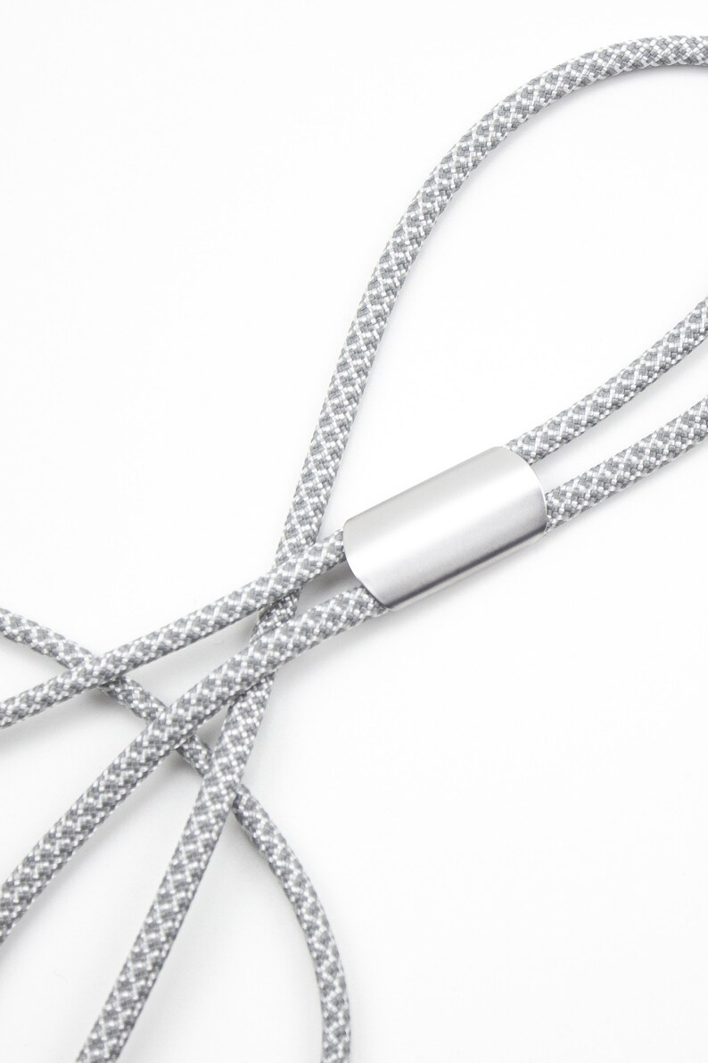 May include: A gray and white patterned lanyard with a silver metal clasp.