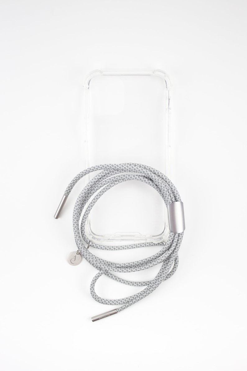 May include: A clear phone case with a gray and white patterned phone strap. The strap has a silver metal clasp and a silver charm.