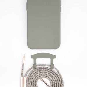 May include: A sage green phone case with a matching lanyard. The lanyard is a woven rope design in shades of gray and beige, with a rose gold-colored metal clasp and accents. The phone case has the brand name "ellenna" printed on the side.