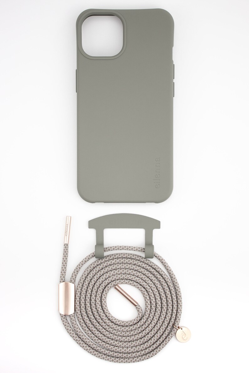 May include: A sage green phone case with a matching lanyard. The lanyard is a woven rope design in shades of gray and beige, with a rose gold-colored metal clasp and accents. The phone case has the brand name "ellenna" printed on the side.