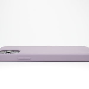 May include: A light purple silicone phone case for a smartphone. The case has a raised camera bump and a button on the side.