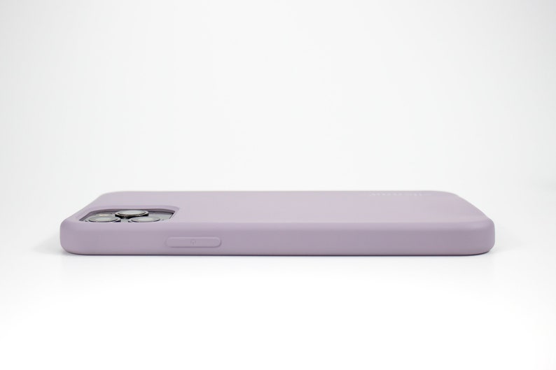 May include: A light purple silicone phone case for a smartphone. The case has a raised camera bump and a button on the side.