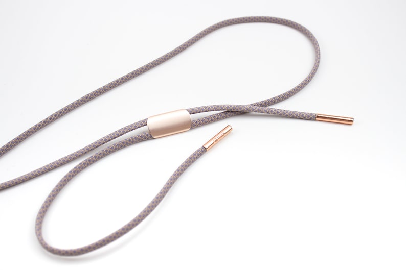May include: A gray and white patterned lanyard with a rose gold metal slider and end caps.