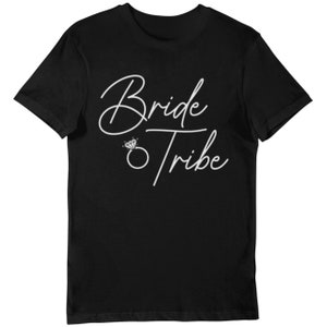 May include: Black t-shirt with white script text that reads "Bride Tribe" with a diamond ring graphic. The shirt is a crew neck style and made of a soft material.