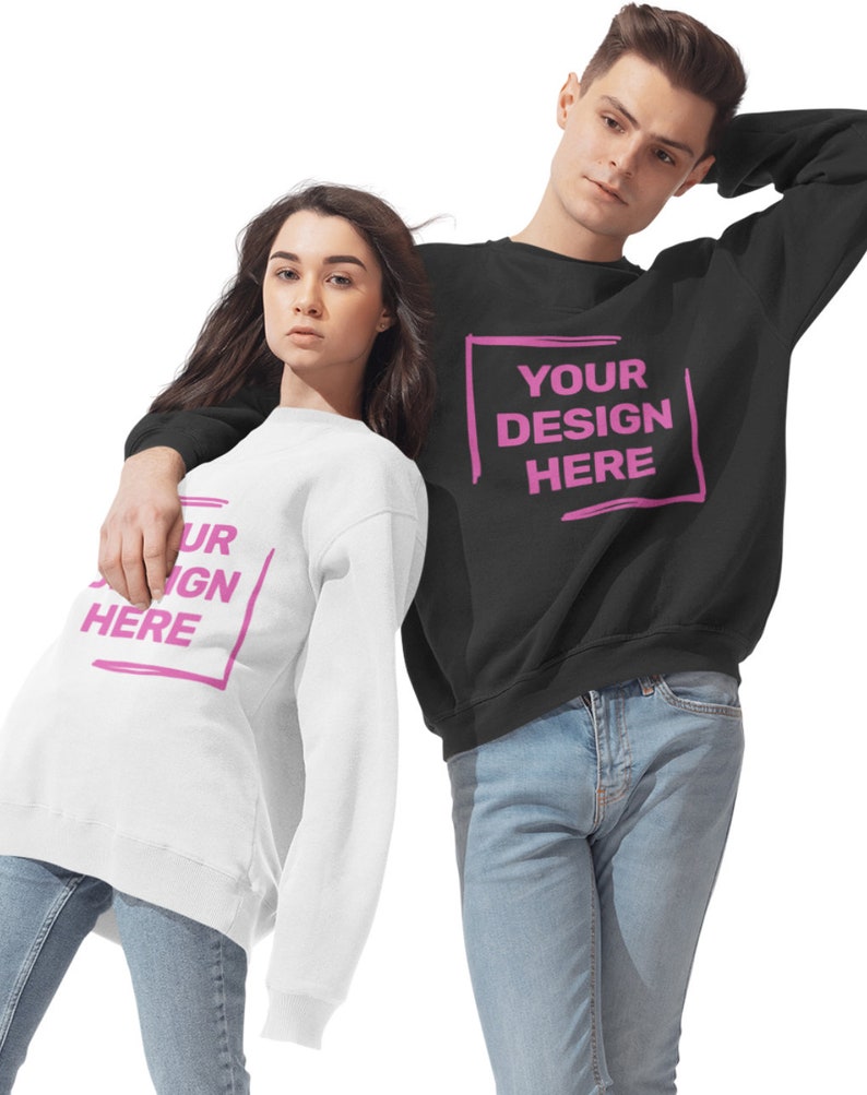 May include: Two people wearing black and white sweatshirts with the text "YOUR DESIGN HERE" printed in pink. The sweatshirts are a classic crew neck style.