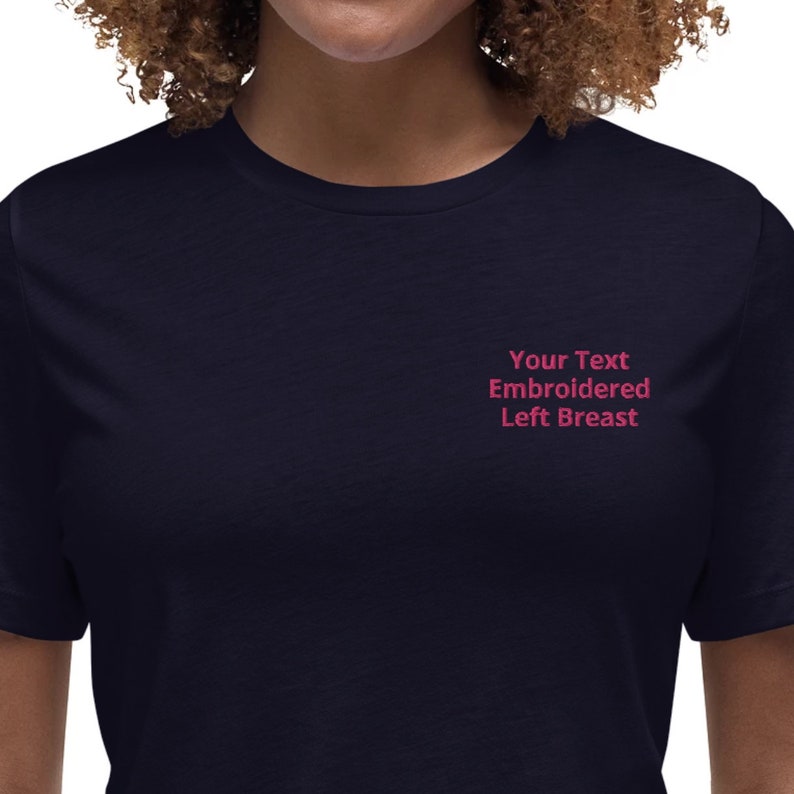 May include: A navy blue t-shirt with the text "Your Text Embroidered Left Breast" embroidered on the left side of the chest.