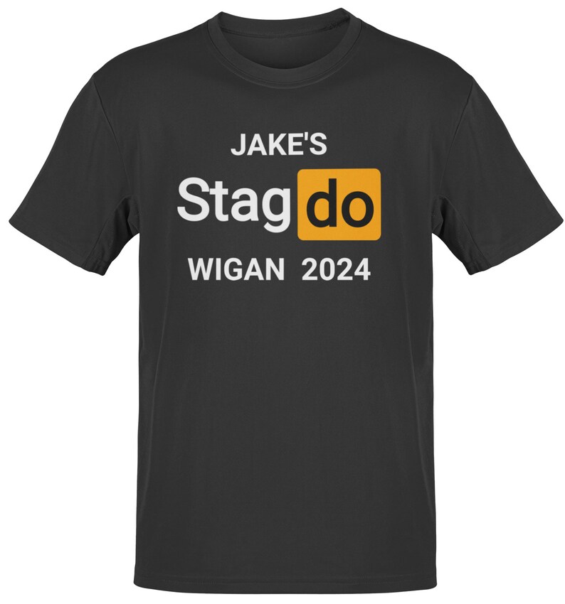 May include: Black t-shirt with white text that reads "JAKE'S Stagdo WIGAN 2024". The word "Stagdo" is in a yellow box.