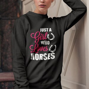 May include: Black sweatshirt with the text "Just a Girl Who Loves Horses" in pink and white lettering with two white horseshoes.