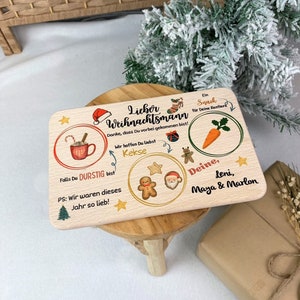 May include: A wooden Christmas sign with a Santa Claus, gingerbread man, and a mug of hot chocolate. The sign says "Lieber Weihnachtsmann" and "Danke, dass Du vorbei gekommen bist!"  It also says "Falls Du durstig bist" and "PS: Wir waren dieses Jahr so lieb!"