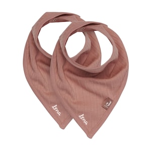 Puede incluir: Dos baberos bandana de color rosa con textura de canalé y el nombre "Lena" bordado en cada uno. Los baberos tienen un cierre de presión.