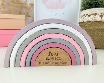 May include: A wooden rainbow stacking toy with six arches in shades of pink, gray, and white. The bottom arch has a wooden plaque with the name "Leni", the date "13.05.2022", and the time "14:27 Uhr 3470g 52cm".
