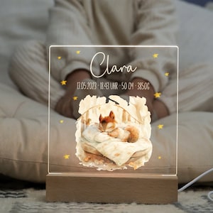 Puede incluir: Una luz nocturna de acrílico transparente con una base de madera. La luz presenta una ilustración de acuarela de un zorro durmiendo en una cama con estrellas y el texto "Clara 13.05.2023 - 18:43 Uhr - 50 cm - 3850g".