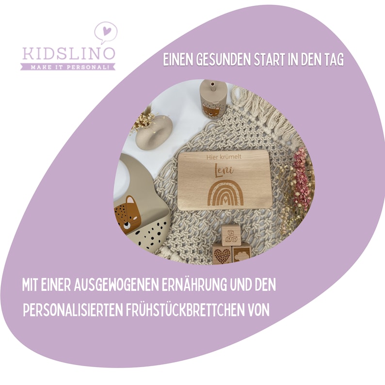 May include: A personalized wooden breakfast board with the name "Leni" engraved on it. The board has a rainbow design and the text "Hier kr&uuml;melt" in German. The board is surrounded by a beige crocheted blanket, a beige silicone bib with a leopard print, and wooden blocks.