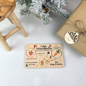 May include: A wooden sign with a Christmas theme. It says "Lieber Weihnachtsmann" and has a gingerbread man, Santa Claus, a cup of hot chocolate, a carrot, and a star. It also says "Danke, dass Du vorbei gekommen bist!" and "Wir hoffen Du Liebst Kekse". The sign is signed "Deine, Leni, Maya & Marlon".