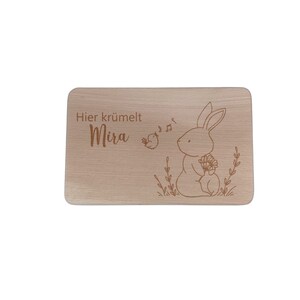 May include: A wooden cutting board with the text "Hier kr&uuml;melt Mira" and a drawing of a rabbit holding flowers.
