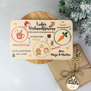 May include: A wooden sign with a Christmas theme. It says "Lieber Weihnachtsmann" and has illustrations of a mug of hot chocolate, cookies, a carrot, and Santa Claus. The sign also says "Danke, dass Du vorbei gekommen bist!" and "Wir hoffen Du liebst Kekse". It is signed "Deine, Leni, Maya & Marlon".