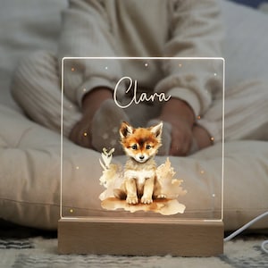 Könnte beinhalten: Ein Nachtlicht aus Holz mit einer durchsichtigen Acrylscheibe, auf der eine Aquarell-Illustration eines Fuchses und der Name "Clara" zu sehen sind.