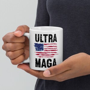 May include: White ceramic coffee mug with a distressed American flag and the text "ULTRA MAGA" in black.