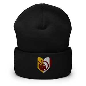 May include: Black beanie with a heart-shaped emblem. The emblem features a yellow and white section with a peace sign and a profile silhouette. The other section is red and white.