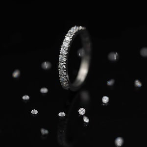 May include: A thin silver band with small diamonds set in a continuous line around the band.